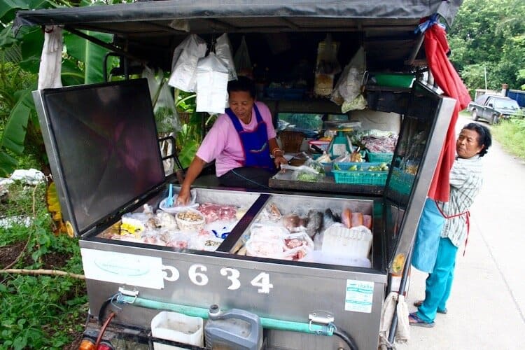 Thai street vendor with cart selling fruits and vegetables