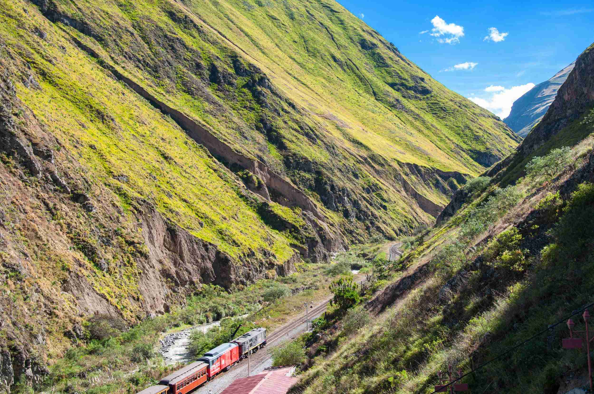 Train traveling through narrow canyon with steep mountainous sides in Ecuador