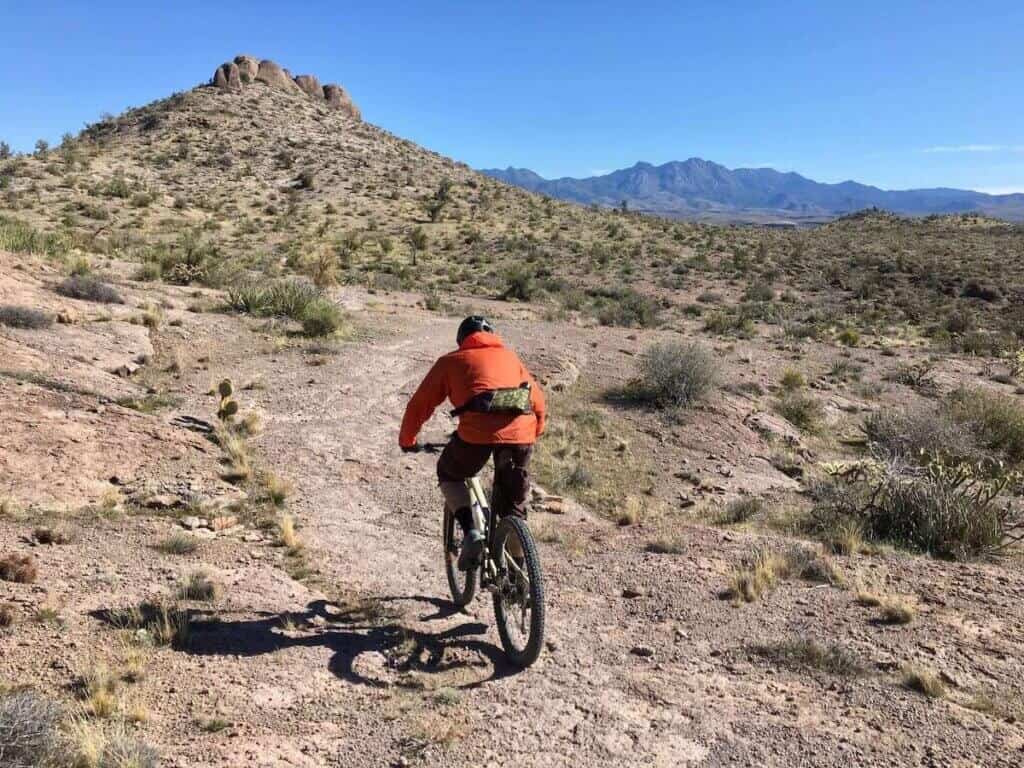 Mountain biker riding away from camera on singletrack trail in desert landscape of Kingman, Arizona