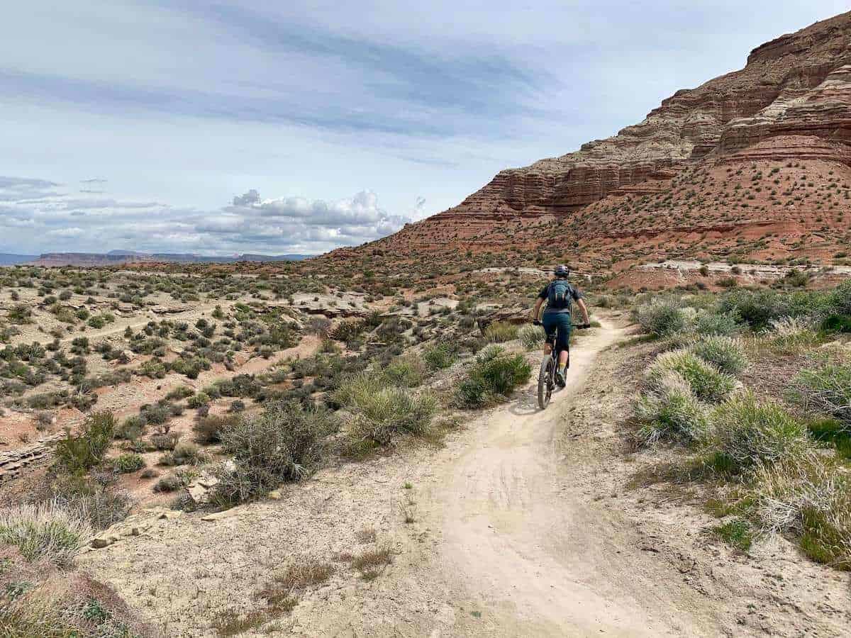 Mountain biker riding away from camera on desert singletrack trail in Hurricane, Utah