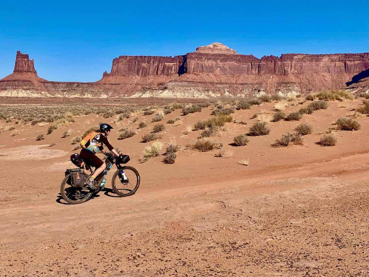 Female bikepacking pedaling along remote doubletrack on the White Rim Trail in Moab