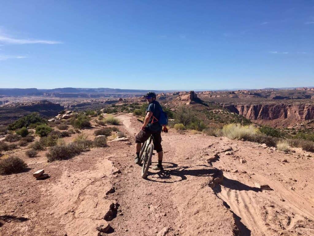 Mountain biker stopped on wide desert slickrock trail called The Whole Enchilada in Moab