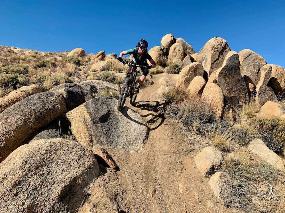 Female mountain biker descending technical and rocky section of trail.
