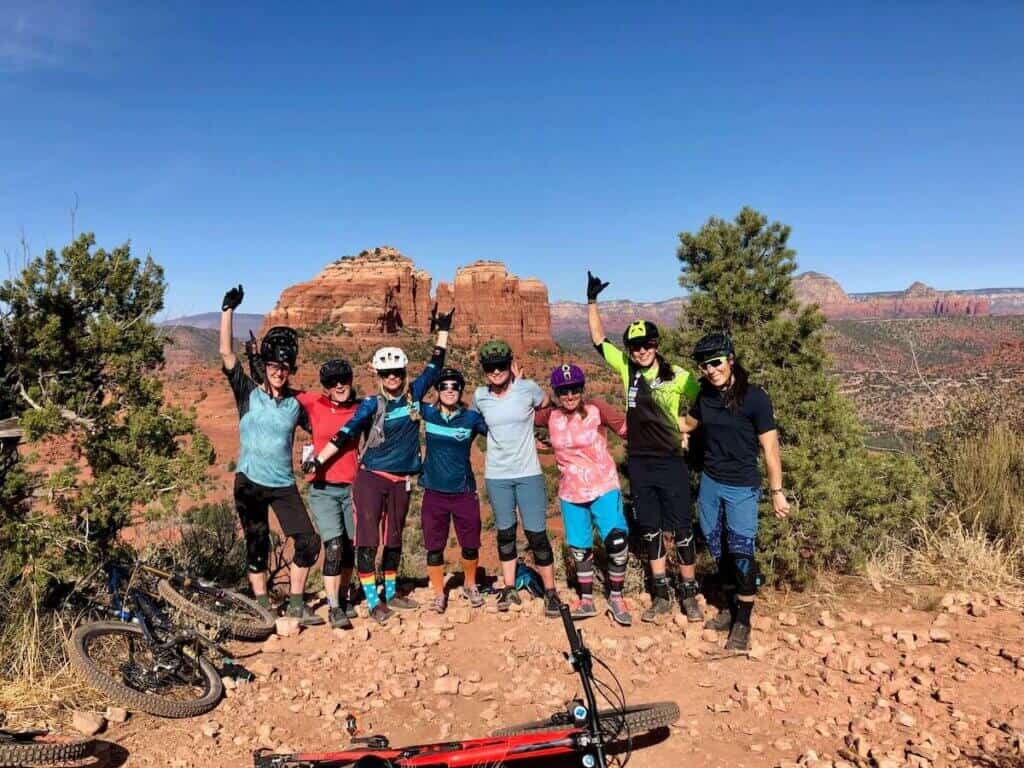 Group of women mountain bikers standing next to each other posing for photo on trail in Sedona Arizona
