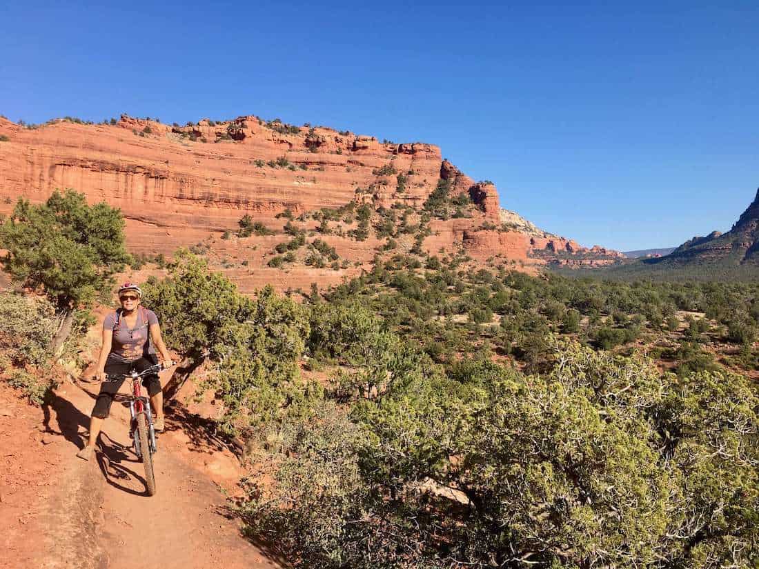 Mountain biker stopped on trail in Sedona for photo with red rock bluffs in background