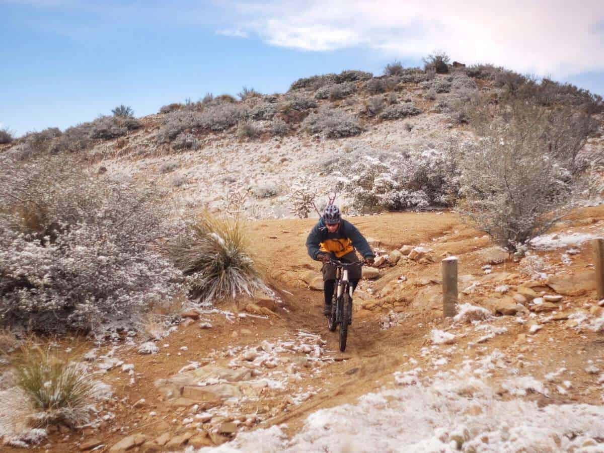 Mountain biker riding trail with dusting of snow on ground