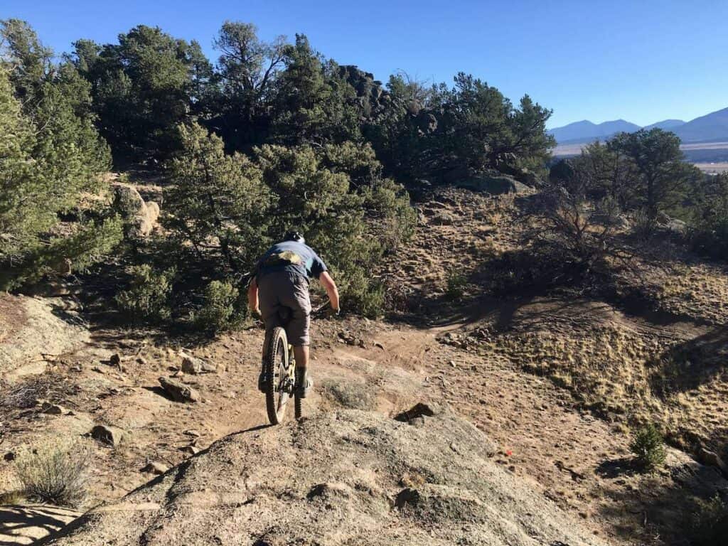 Mountain biker riding bike down rock roller on trail in Buena Vista, Colorado
