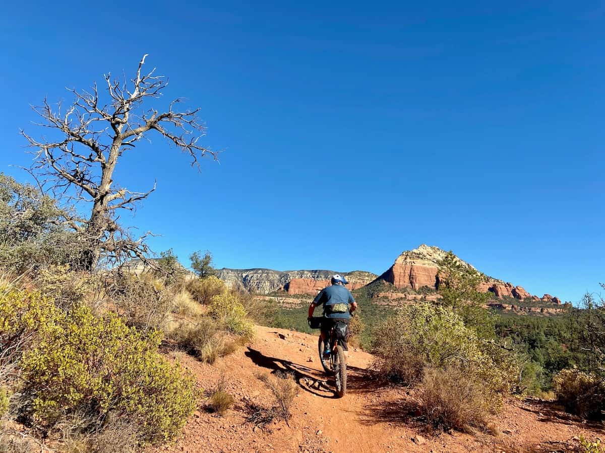 Mountain biker on red dirt singletrack trail in Sedona beautiful red rock formations in distance