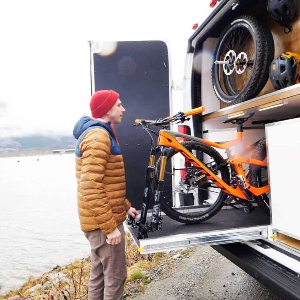 Man sliding mountain bike out on tray from rear of van