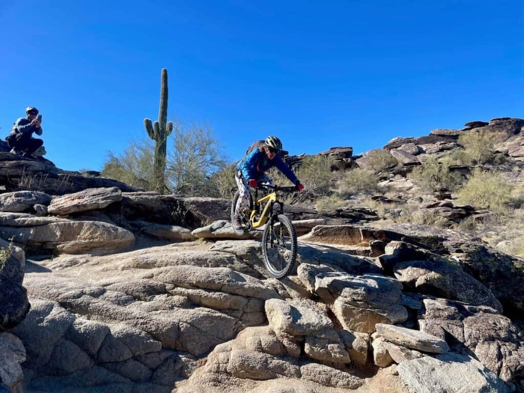 Woman riding mountain bike down rock feature on National Trail South Mountain in Phoenix