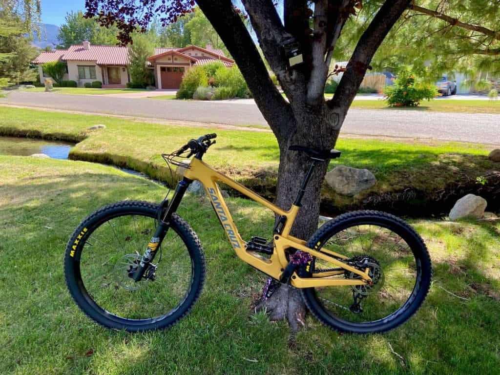 Yellow Santa Cruz Bronson mountain bike leaning against tree in grassy yard