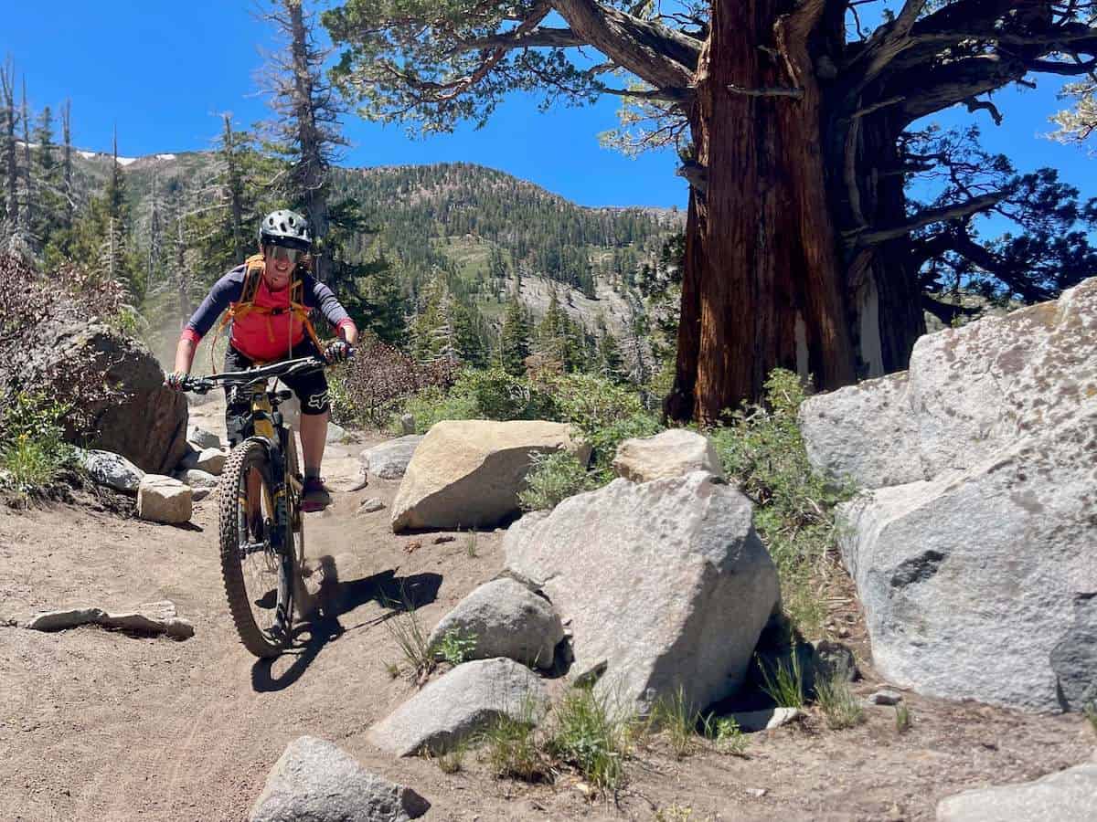 Female mountain biker riding bike down rocky and sandy trail in California
