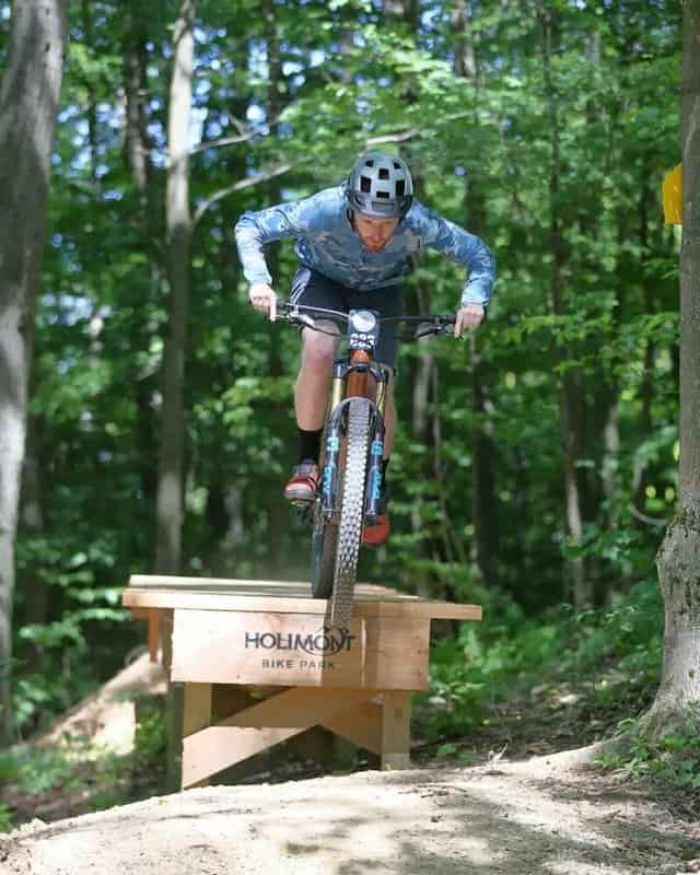 Mountain biker going off wooden drop at HoliMont Bike Park in New York