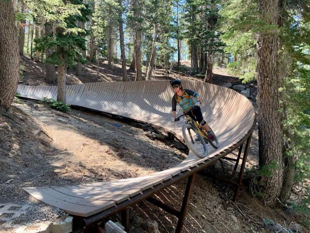 Mountain biker riding bike on elevated wooden berm at Mammoth Mountain Bike Park in California
