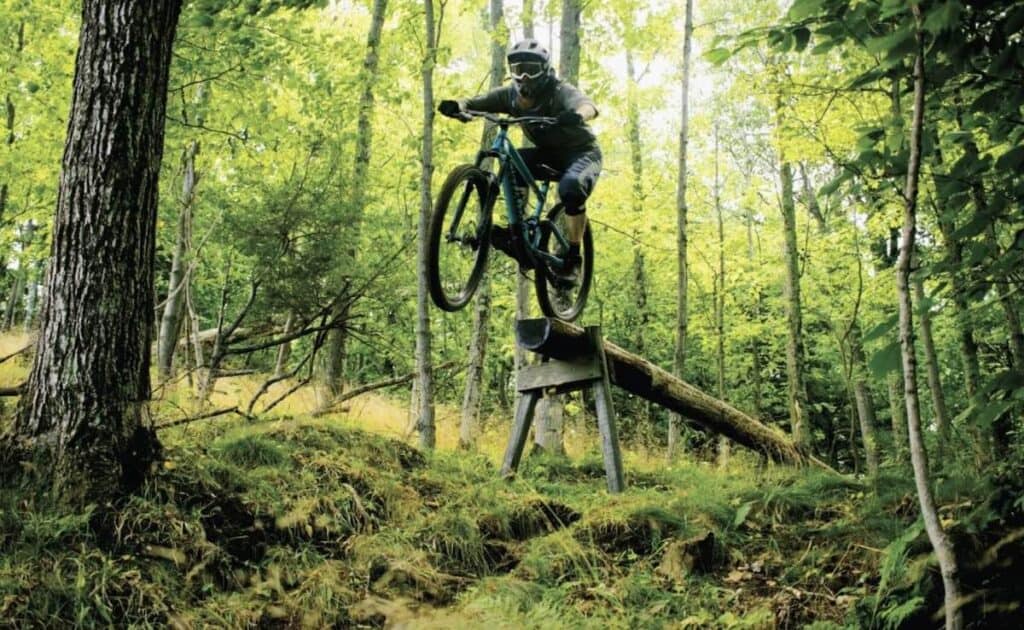 Mountain biker riding off skinny log drop at Marquette Mountain Bike Park in Michigan