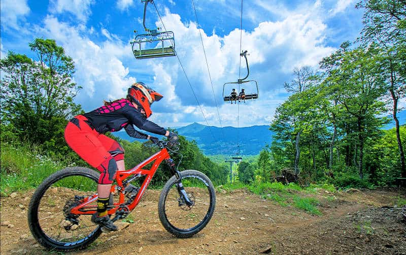 Mountain biker on trail underneath chairlift at Sugar Mountain Bike Park in North Carolina