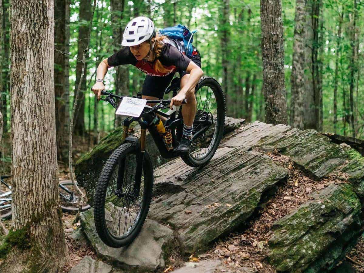 Female mountain biker riding down rock slab on trail in Vermont