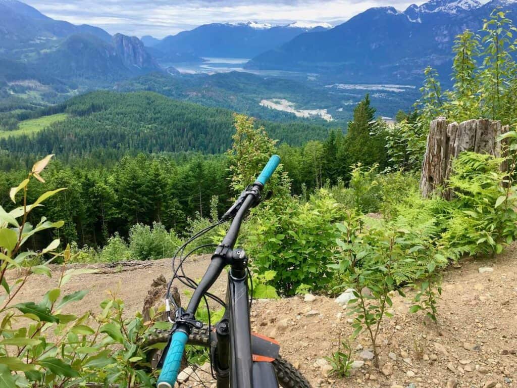 View out over front of mountain bike handlebars onto mountain and fjord landscape in Squamish, BC 