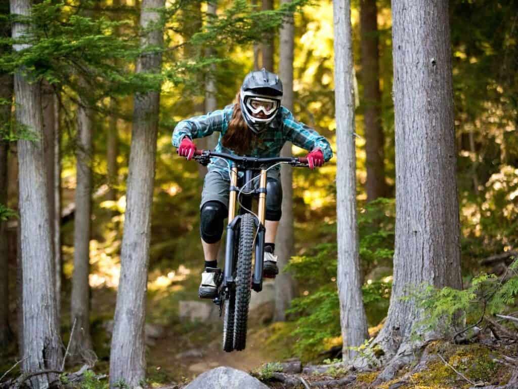 Female mountain bike wearing mountain bike protective gear riding bike down trail at high speed