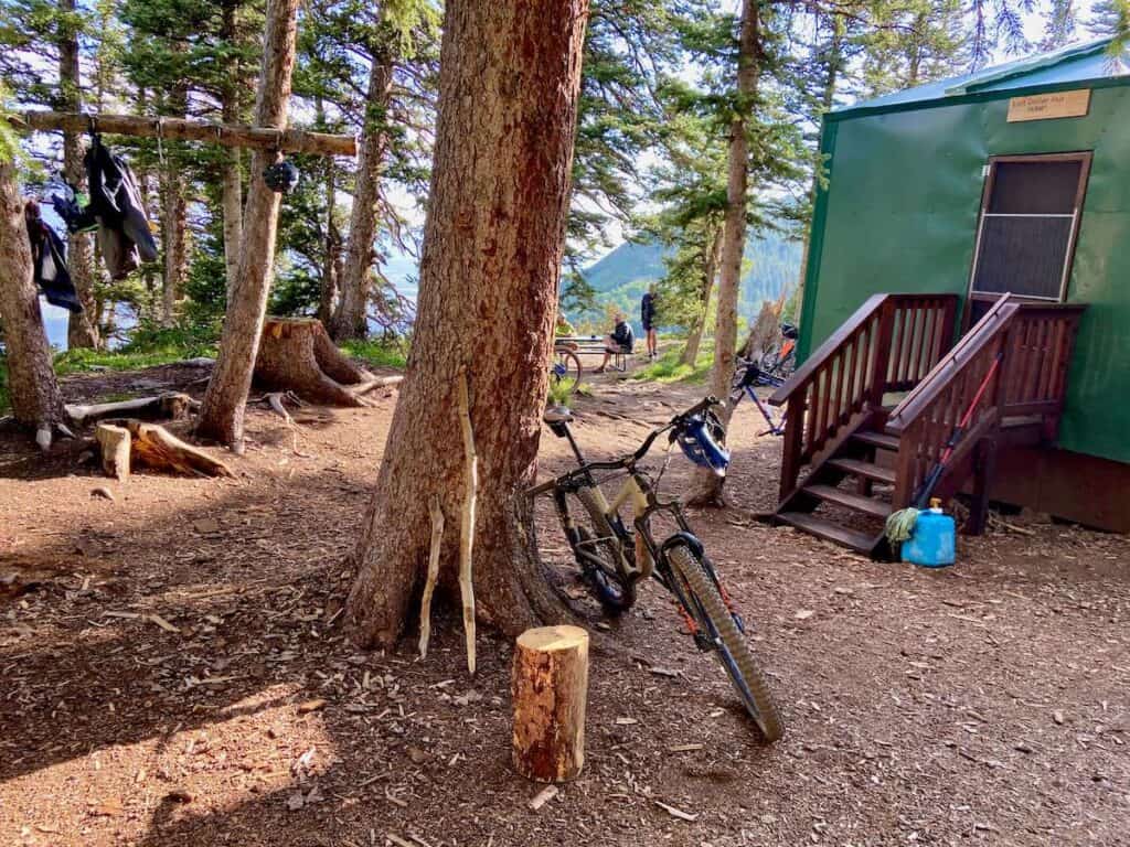 Mountain bike leaning against tree in front of backcountry hut on Telluride to Moab bike route
