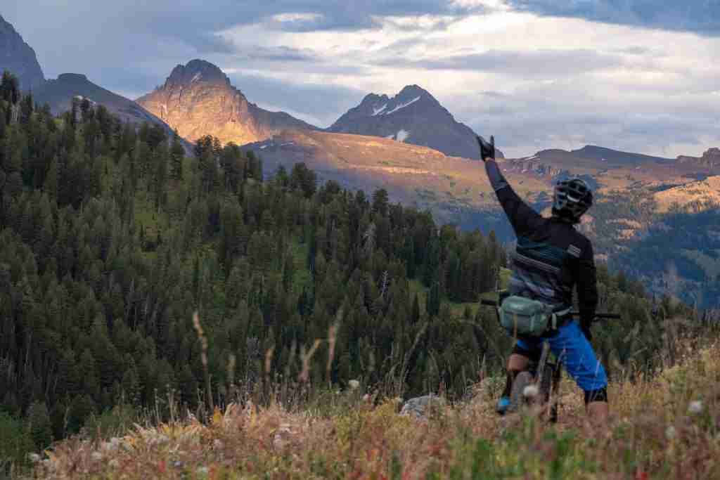 Mountain biker with one arm raised on trail near Grand Targhee in Wyoming