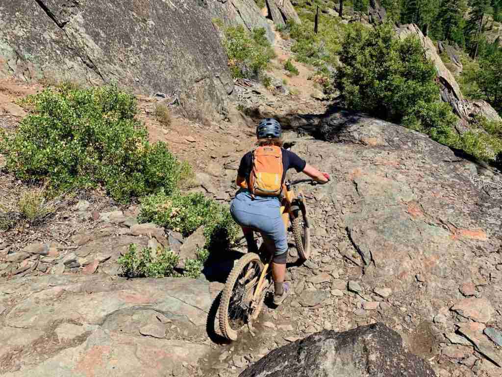 Mountain biker riding bike down rocky section of trail in California