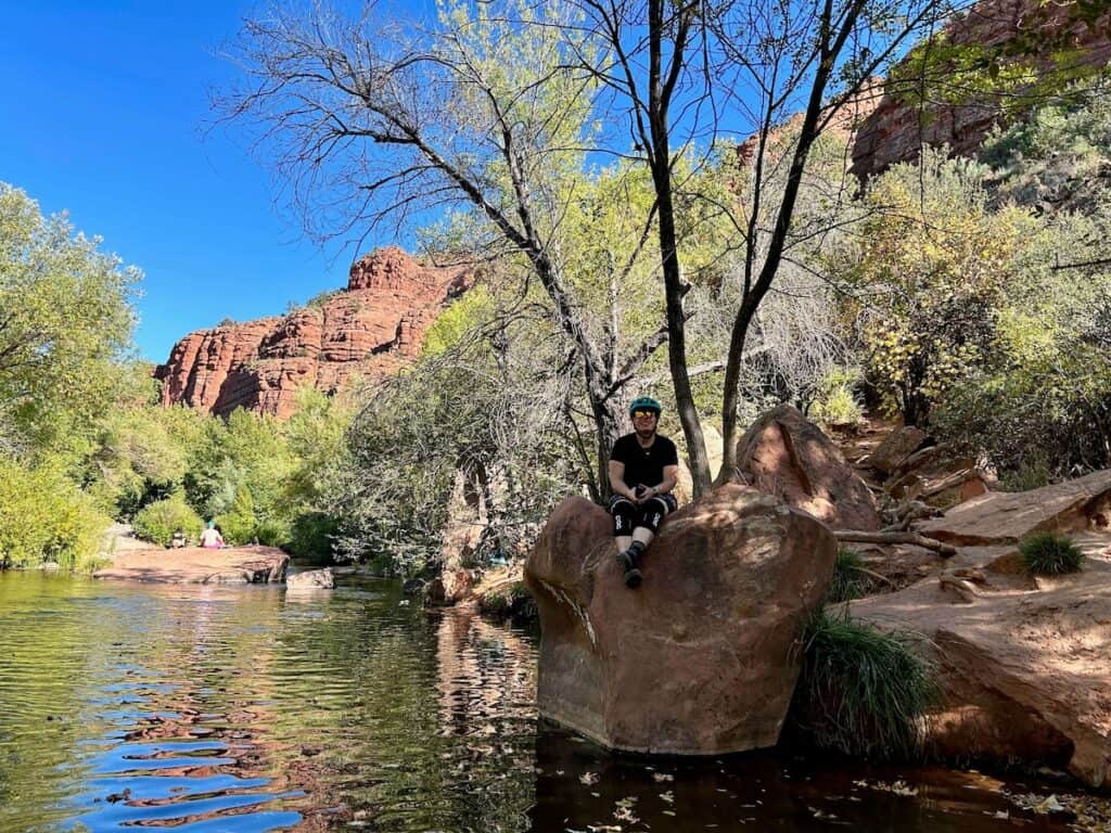 Female mountain biker sitting on rock above Oak Creek River on a break