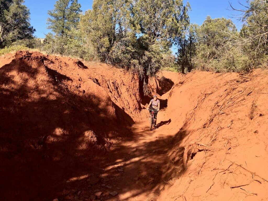 Mountain biker riding through trench-like trail called Canyon of Fools in Sedona
