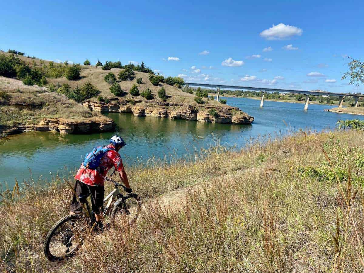 Mountain biker riding on trail next to Wilson Lake Reservoir in Switchgrass trail network in Kansas