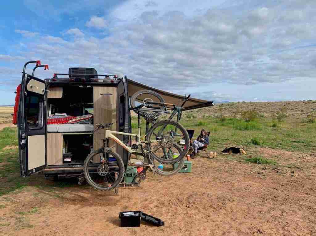 Camper van set up in dispersed campsite with bikes and gear spread out