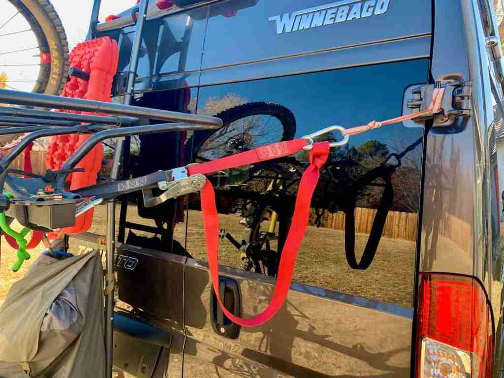 Showing vertical hanging bike rack stabilized to back of van with quick-release ratchet straps
