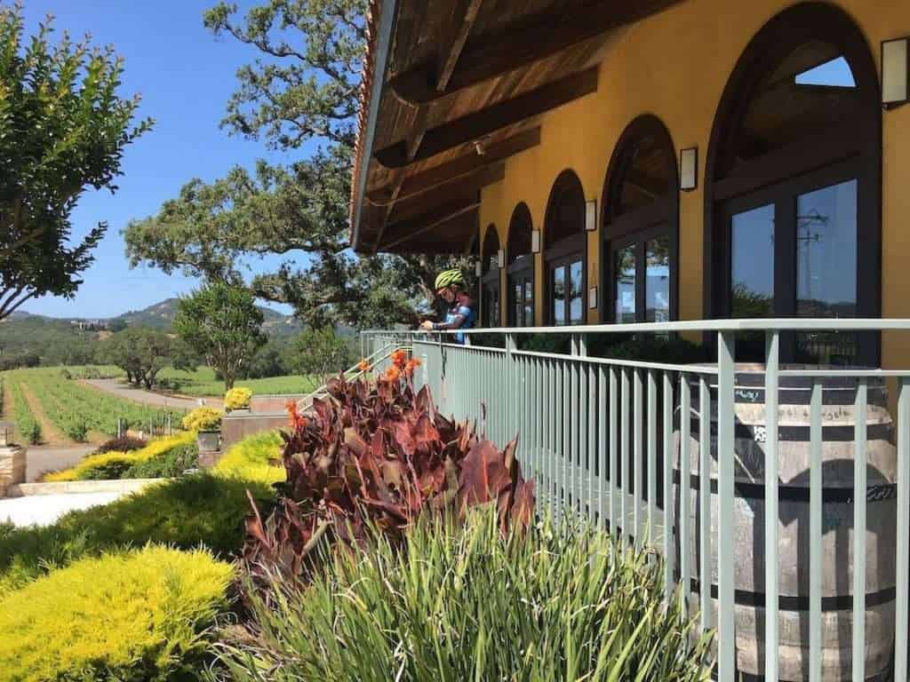 Cyclist in gear standing on front porch of Tuscan-style winery in California
