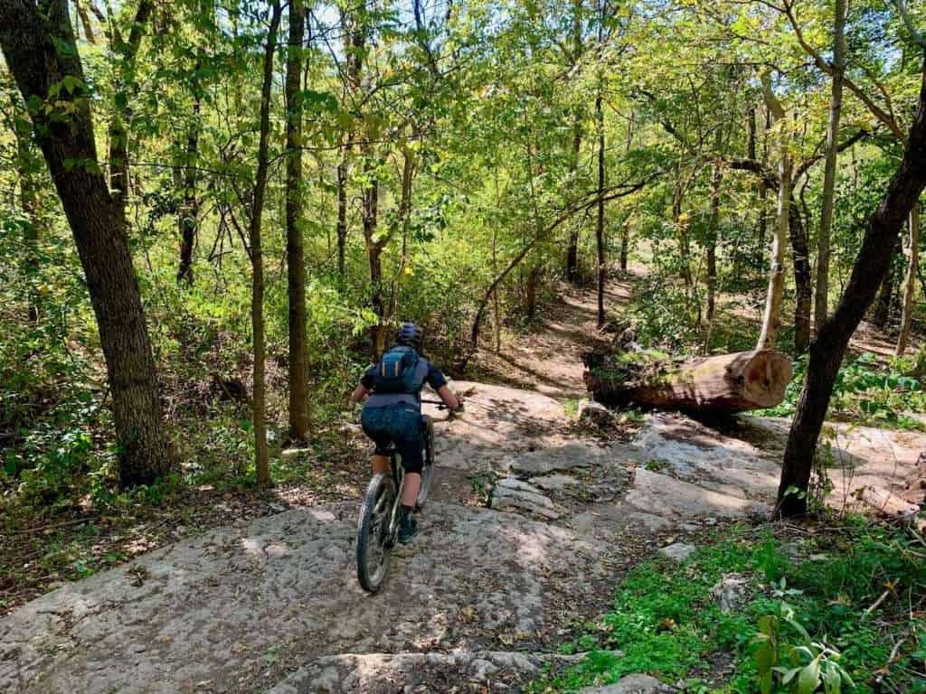 Mountain biker riding down rocky singletrack trail through the woods in Bentonville, Arkansas