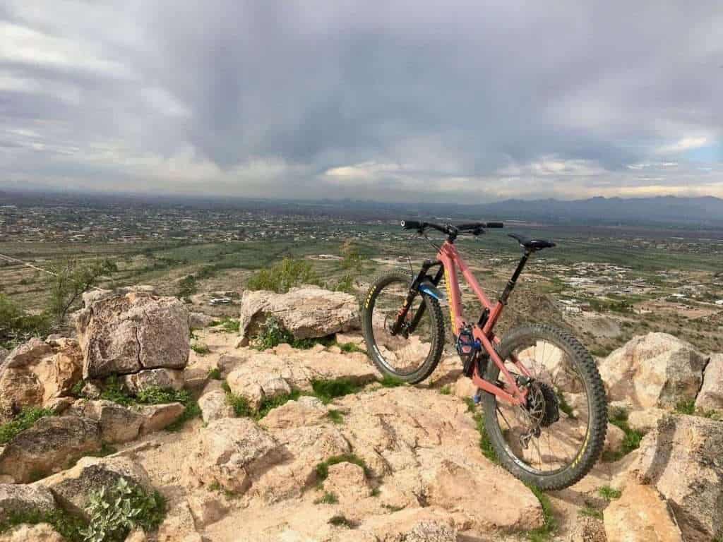Mountain bike propped up on rocks at overlook near Phoenix, Arizona with moody clouds overhead