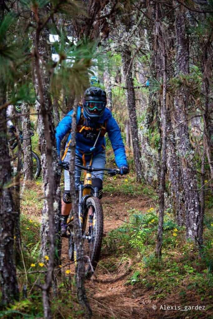 Mountain biker wearing full-face helmet riding singletrack through the woods in Oaxaca, Mexico