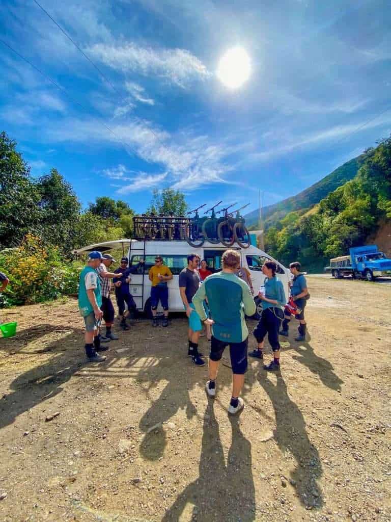 Group of mountain bikers standing around outside of shuttle van post-ride with mountain bikes on top during mountain bike trip to Oaxaca