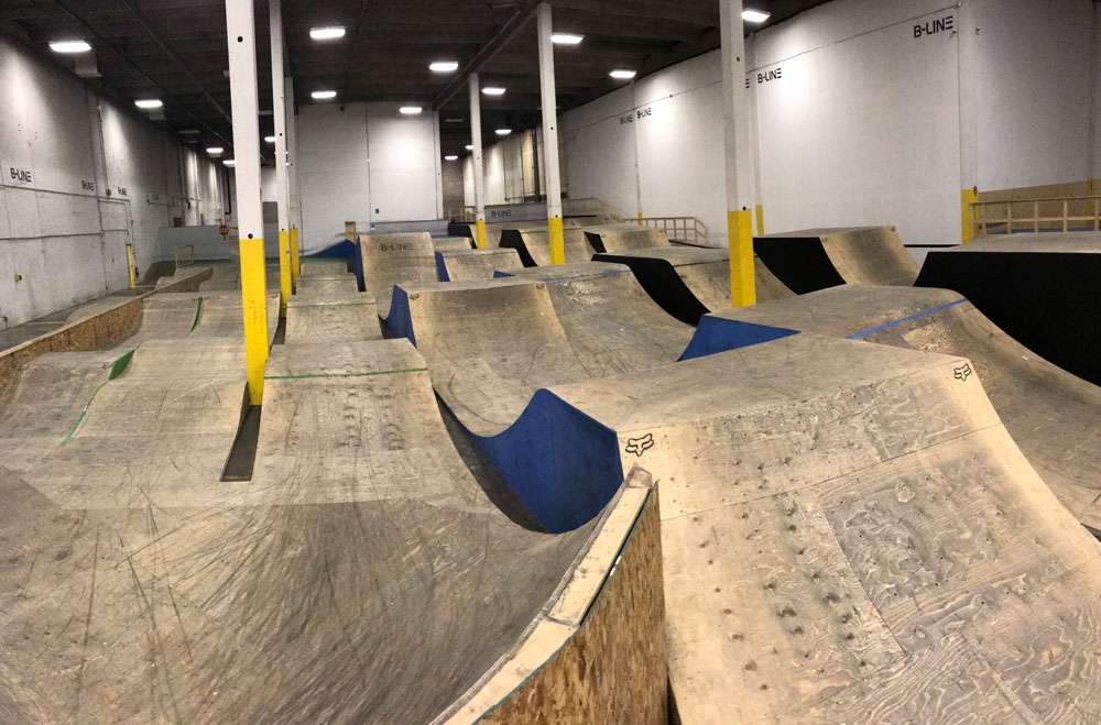 Inside B-Line indoor bike park in Calgary with wooden ramps, jumps, and features