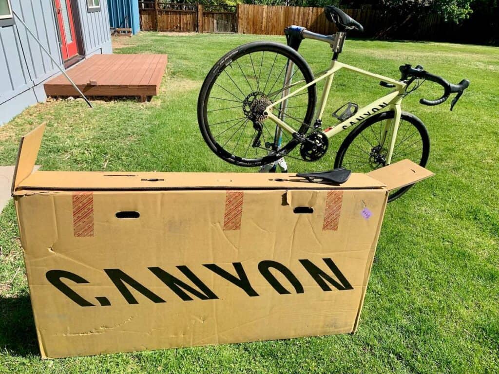 Bike box with Canyon written on it and road bike on bike stand in back