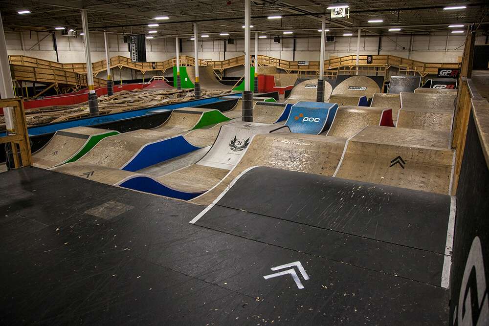 Inside of Joyride 150 indoor bike park with wooden jumps, ramps, and features