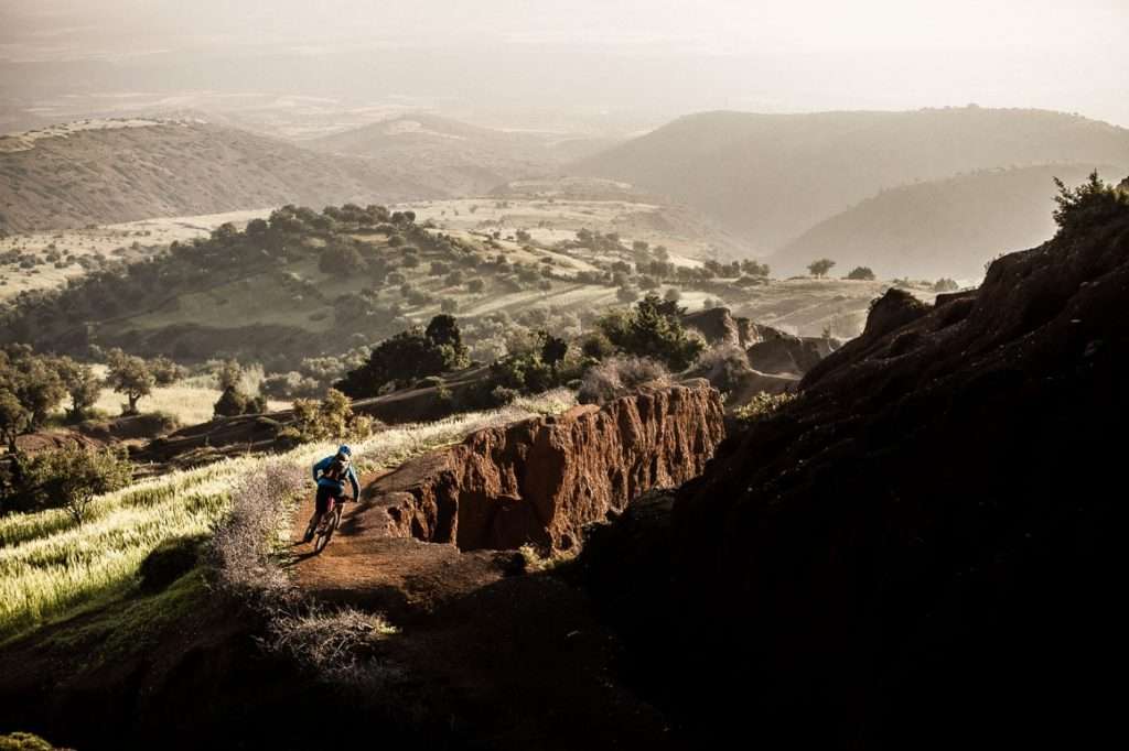 Mountain biker riding down red singletrack trail in Morocco