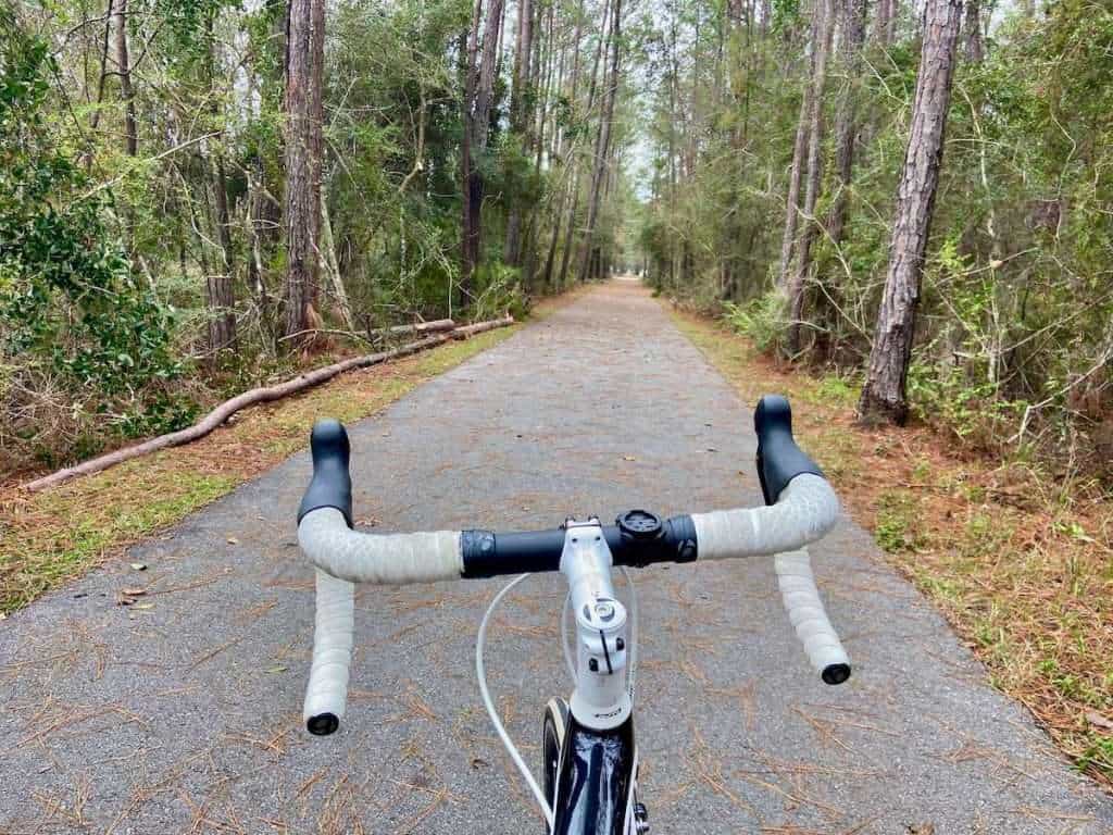 Photo out over road bike handlebar on straight Tammany Trace pave rail trail path near New Orleans, Louisiana