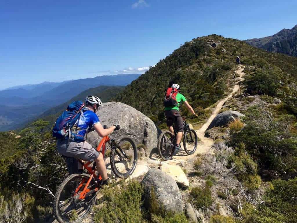 Two mountain bikers riding along ridge trail in New Zealand