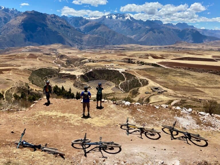 mountain bikers stopped to take in the views of Incan ruins in Peru with Andes mountains in the distance