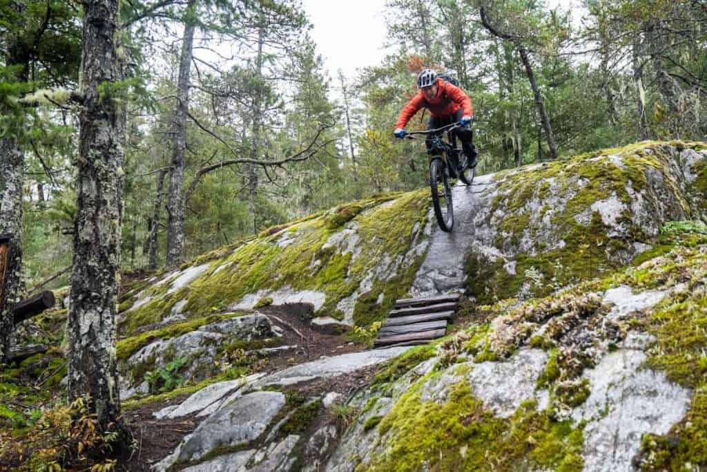 Mountain biker riding down wet, slippery rock slab in British Columbia