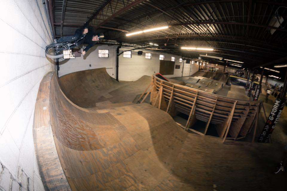 Inside view of the Wheel Mill indoor bike park with wooden ramps and jumps