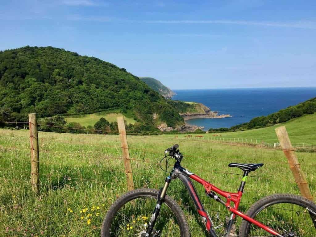 Bike leaning against fence overlooking idyllic green pastures by the ocean in England