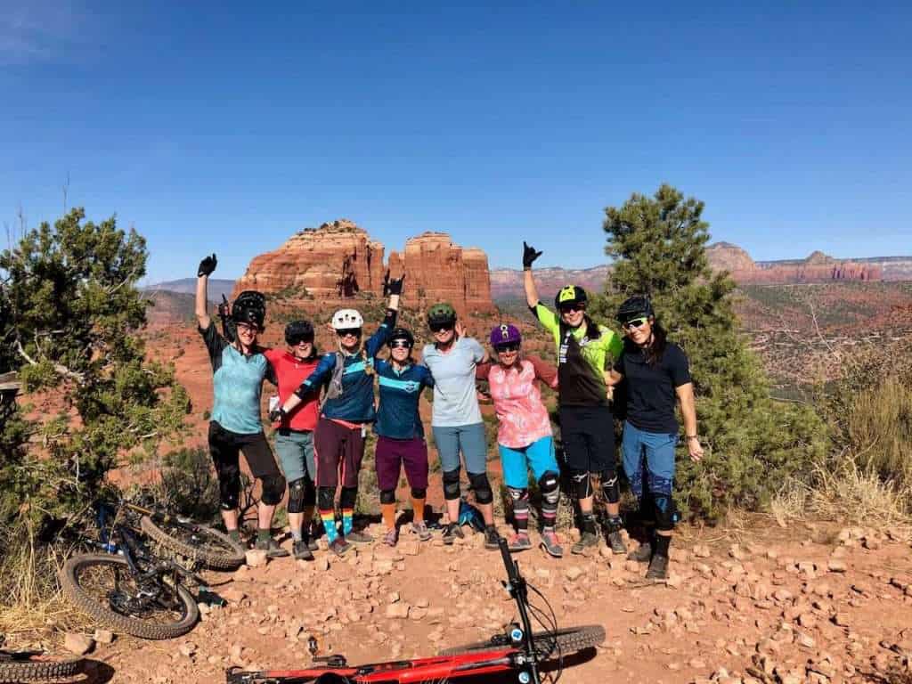Group of 8 women mountain bikers posing for photo in Sedona with beautiful red rocks in background