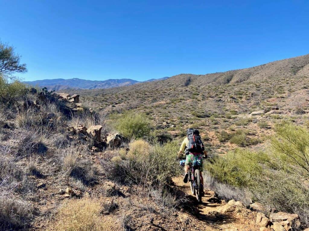 Bikepacker riding bike down rocky section of the Black Canyon Trail in Arizona