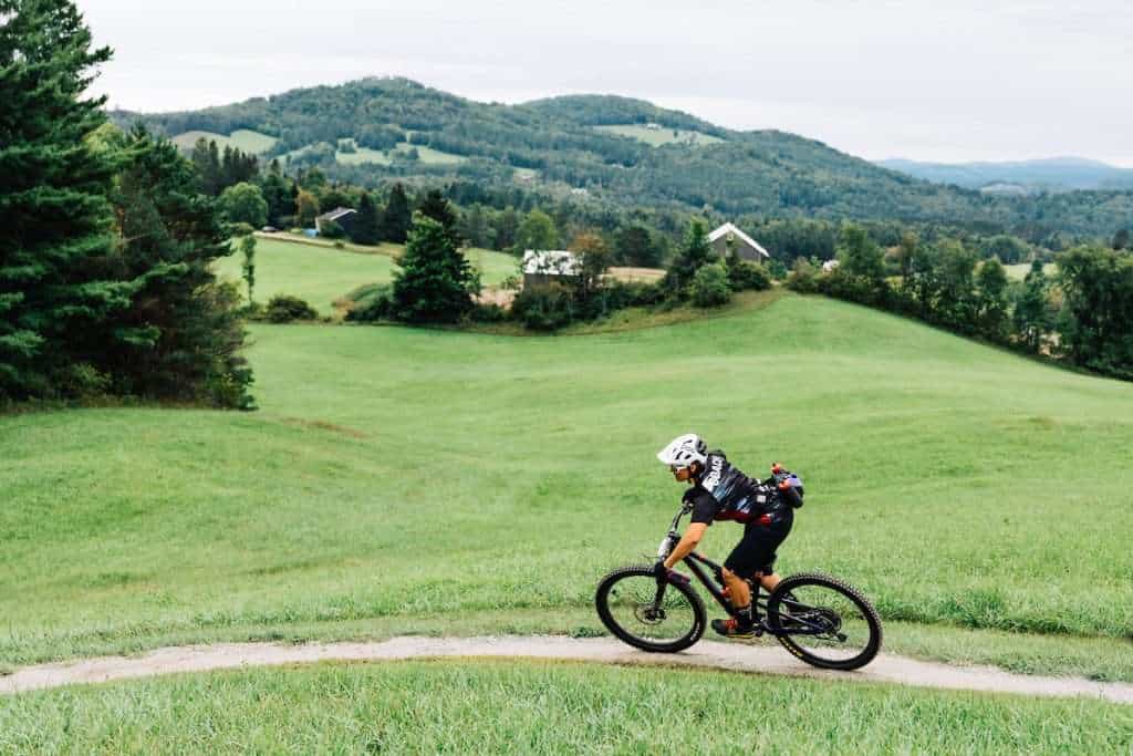 Female mountain biker riding singletrack trail in East Burke, Vermont at Kingdom Trails