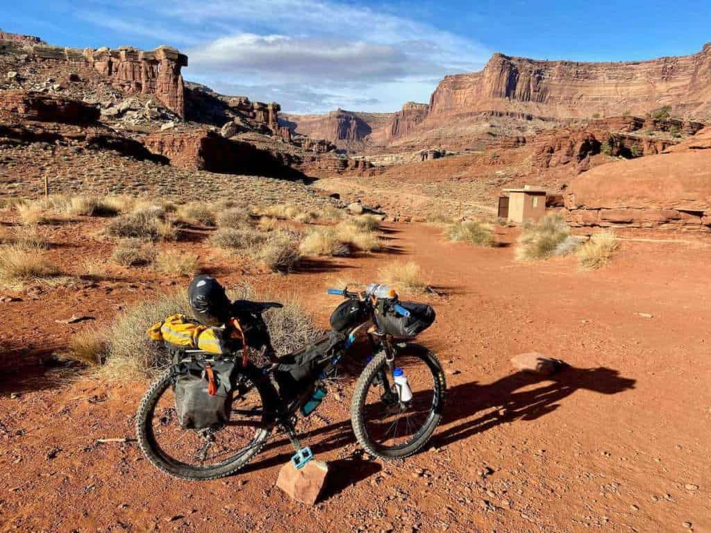 Fully loaded Santa Cruz Chameleon bikepacking bike propped up on a rock on the White Rim Trail in Moab, Utah